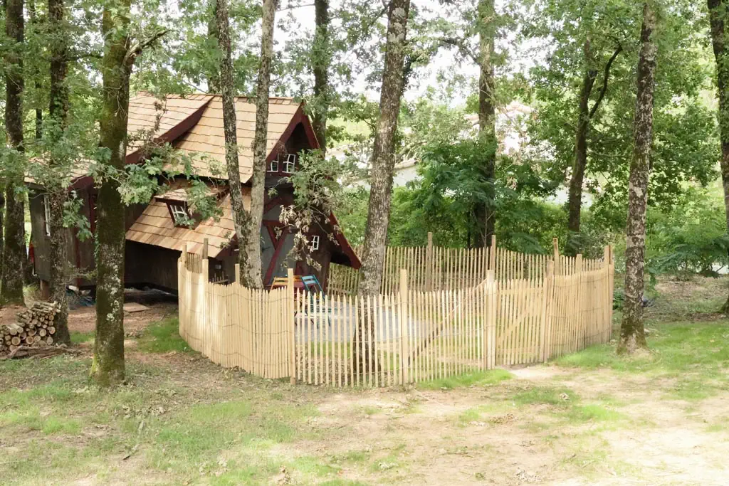 Clôture en ganivelle Photo d'une clôture réalisée avec des piquets sciés écorcés et de la ganivelle, et séparant un jardin dans un gîte